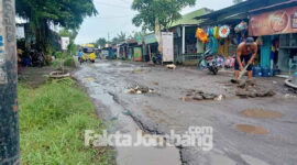 Tampak seorang warga setempat saat menimbun jalan berlubang dengan batu seadanya di jalan jurusan Tapen - Kabuh, tepatnya di Desa Tapen, Kecamatan Kudu, Kabupaten Jombang,